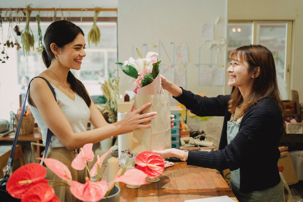 Eine Floristin verkauft Blumen an eine Frau.